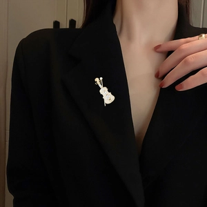 Detailed view of an elegant gold violin brooch with rhinestones on a black suit