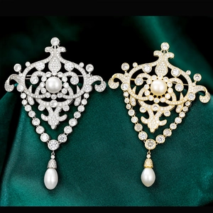 Détails de broches baroques avec perles naturelles et zircons sur fond de soie