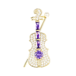 Macro shot of violin brooch with purple gemstones, white zircon, and a pearl accent