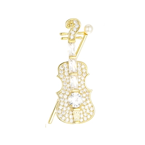 Detailed view of golden violin brooch with micro-pave crystals and a white pearl