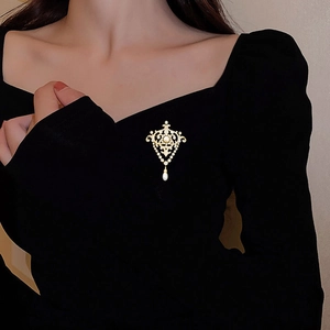 Détail de la broche perle baroque avec zircons sur robe noire montrant le style vintage