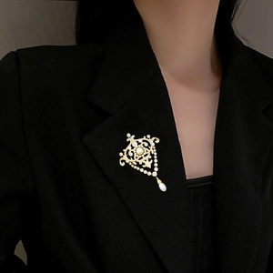 Broche vintage en perles et zircons dorés sur blazer noir pour un style palais