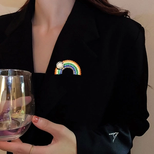 Close-up of rainbow brooch with white flowers and colorful zircons on black blazer