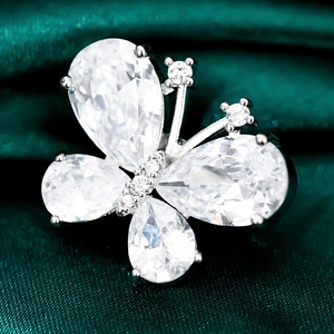 Macro shot of butterfly brooch with pear-cut gemstones on dark green silk fabric