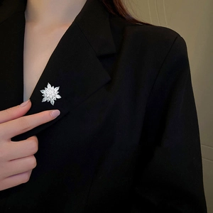 Elegant silver snowflake brooch with sparkling cubic zirconia on a black suit jacket