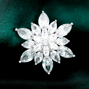 Macro view of snowflake brooch with marquise cut crystals on dark green silk