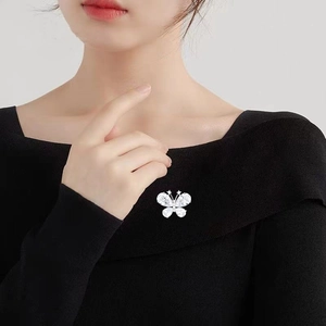 Elegant butterfly crystal brooch with teardrop rhinestones on black fabric suit background