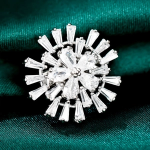 Macro d'une broche fleur argentée avec zircones cubiques sur un tissu en soie vert foncé