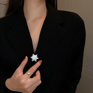 Detailed close-up of a sparkling snowflake brooch with zircons pinned on a black suit blazer