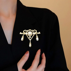 Close-up of vintage gold brooch with zircons and pearls on a black suit jacket
