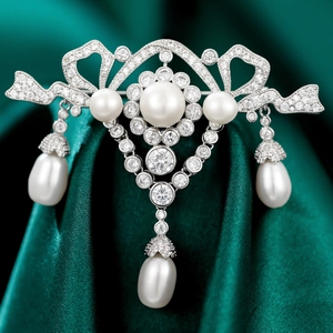 Elegant luxury bow brooch with white pearls and sparkling zircons on green silk background