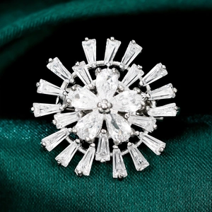 Vue macro d'une broche fleur argentée avec zircons sur fond de velours vert foncé