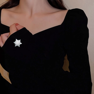 Detailed view of a silver snowflake brooch with marquise cut zircon on a black dress