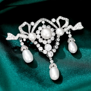 Macro shot of luxury bow brooch with white zircons, round pearls and teardrop drops