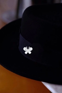 Detailed close-up of a silver butterfly brooch with sparkling zircons on a black hat