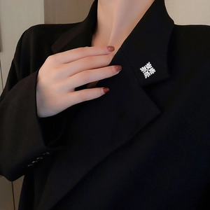Macro shot of silver zircon snowflake brooch on a black suit lapel with elegant detail