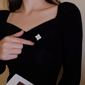 Close-up of a silver snowflake brooch with zircons on a black dress worn by a model