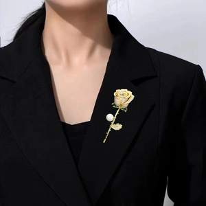 Elegant gold rose brooch with white pearls and zircons pinned on a black suit lapel