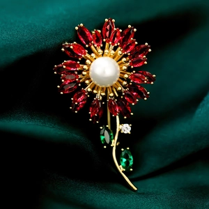 Detail of sunflower brooch with red gems and pearl on green silk fabric backdrop