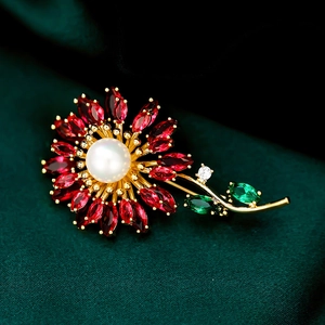 Macro detail of sunflower brooch with red marquise petals and a central white pearl