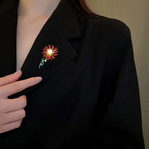 Detail of sunflower brooch with red crystals and pearl on a black blazer jacket