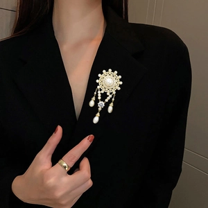 Close-up of vintage gold freshwater pearl brooch with zircon tassels on dark suit