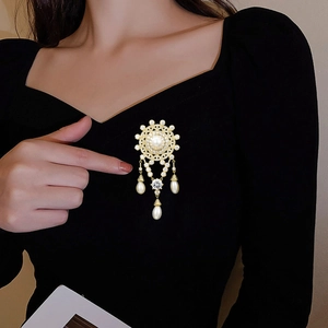Vintage gold pearl brooch with cubic zirconia tassels worn on a black dress