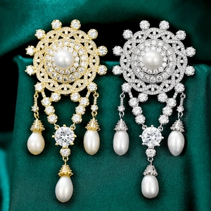 Detailed macro view of vintage baroque brooches with pearls and zircons on green silk