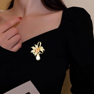 Détail d'une broche fleurie avec une pierre jaune et un pendentif en perle goutte