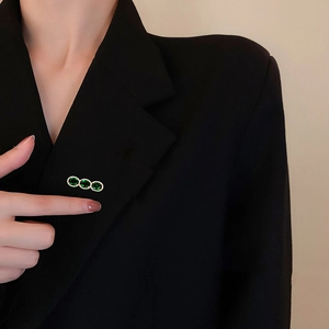 Close-up of triple oval green zircon brooch pinned on a black suit lapel with gold setting