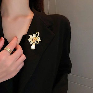 Gros plan d'une broche fleur vintage avec pierre ambre et perle sur un blazer noir