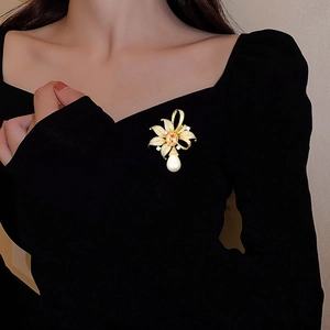 Broche fleur rétro avec cristaux jaunes et perle goutte d'eau sur vêtement noir