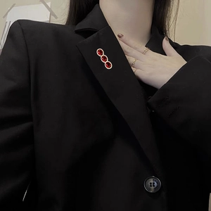 Close-up of triple oval red zircon brooches pinned on a professional black suit lapel