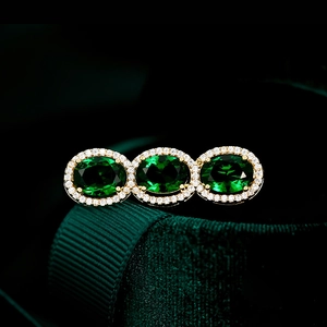 Macro detail of three oval green zircons with halo setting in a gold vintage brooch