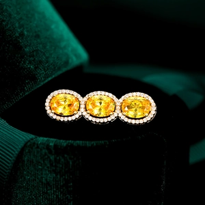 Exquisite triple oval yellow zircon brooch with gold halo setting on velvet