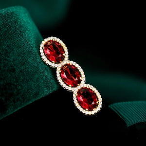 Detail of red zircon oval stones with micro-inlaid halos on a gold-plated brooch