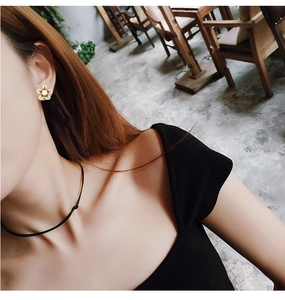 Détail de boucles d'oreilles fleurs dorées avec perle portées par un mannequin en douceur