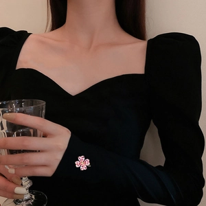 Detail of pink crystal flower clover brooch pinned on black sleeve for elegant accent