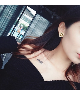 Détail d'une boucle d'oreille fleur à cinq pétales avec perle et zircons sur un mannequin