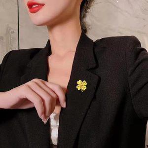 Elegant gold four-leaf clover brooch with crystals pinned on a black blazer lapel
