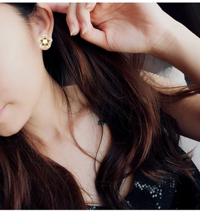 Vue détaillée de boucles d'oreilles fleur avec zircons et perle sur un mannequin