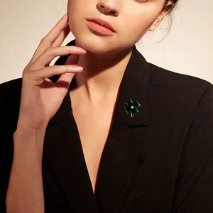 Elegant four-leaf clover brooch with green stones pinned on a black blazer lapel