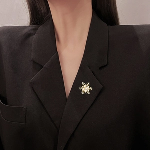 Detail of elegant rotating snowflake brooch with zircon on dark suit lapel