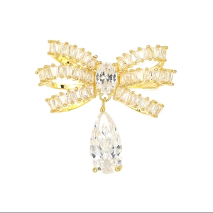Elegante spilla a fiocco dorata con zirconi e un ciondolo a goccia a taglio pera