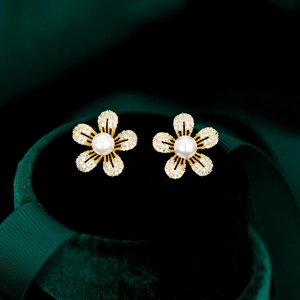 Détail de boucles d'oreilles fleurs avec pétales en zircon et une perle blanche