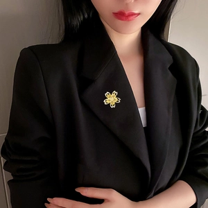 Vue détaillée d'une broche cerisier dorée épinglée sur le revers d'un costume noir