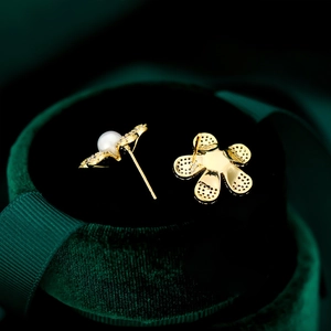 Détail macro de boucles d'oreilles fleur en or avec zircons et perle centrale incrustée