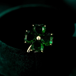 Macro shot of a four-leaf clover brooch featuring deep green heart-shaped gemstones