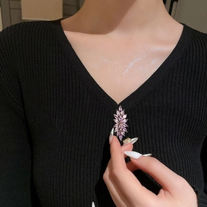 Eleganter lila Zirkon Blumen-Brosche in Goldoptik an einem schwarzen V-Ausschnitt Pullover