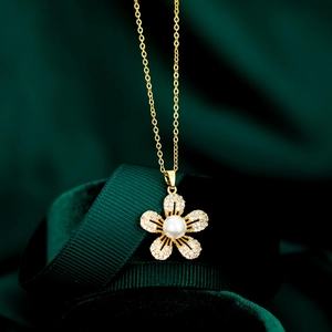 Vue macro du collier fleur dorée serti de zircons avec une perle centrale chic